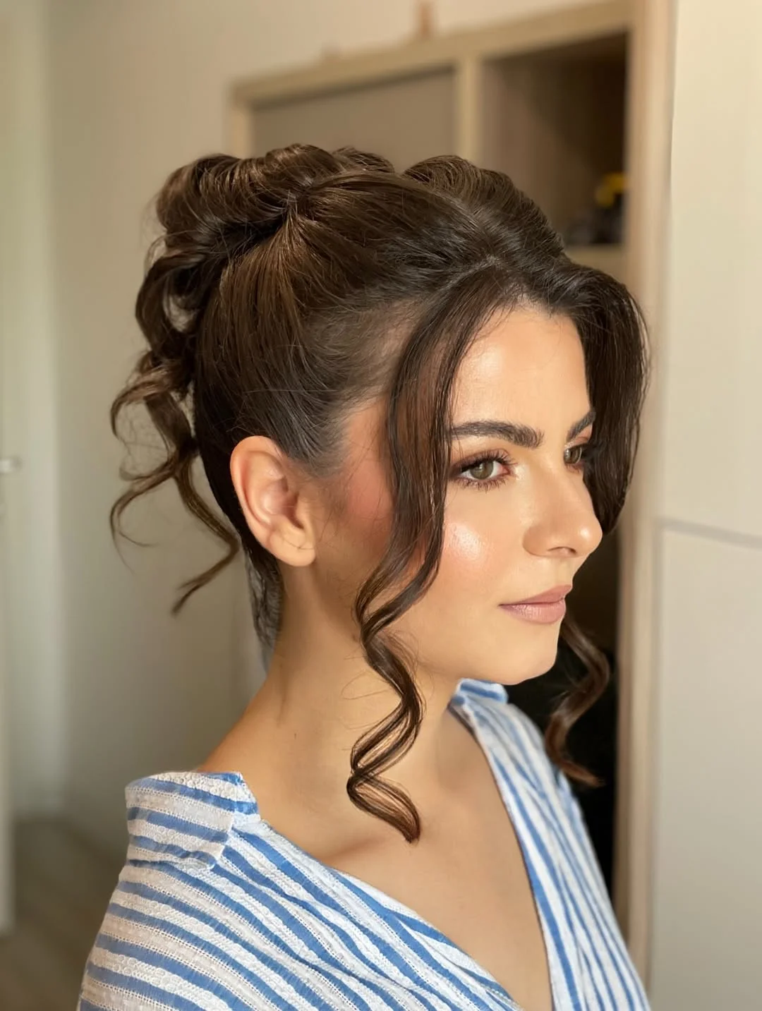 natural summer bun hairstyles 2026 Curly High Bun With Soft Face Framing Tendrils