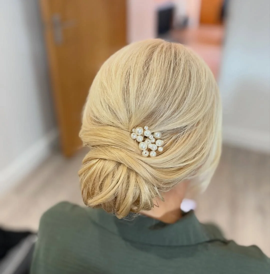 refined summer wedding guest hairstyles 2026 Classic Pearl-Tucked Low Bun for Warm Summer Evenings