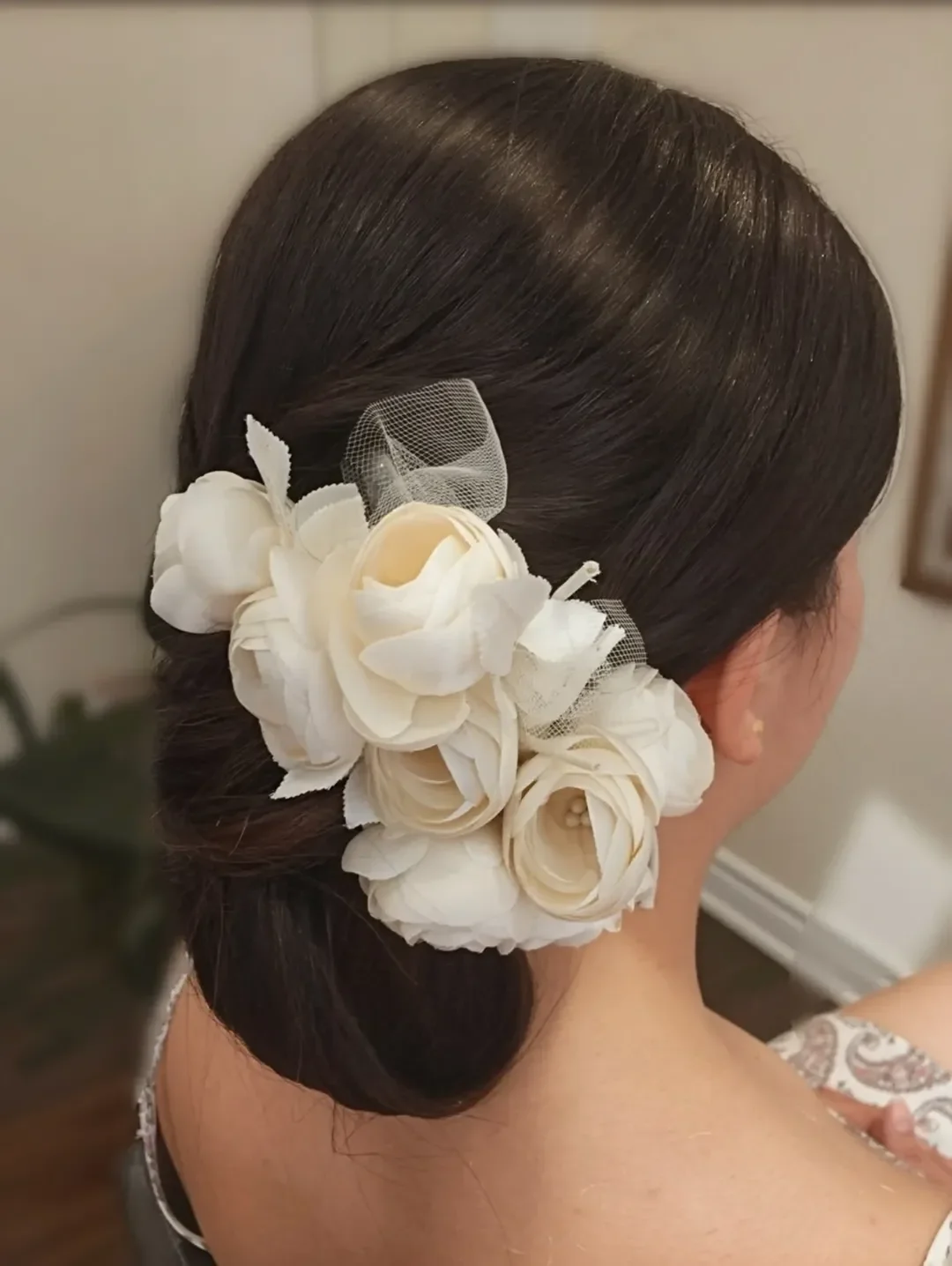 refined summer wedding guest hairstyles 2026 Vintage-Inspired Low Roll With Oversized Floral Accent