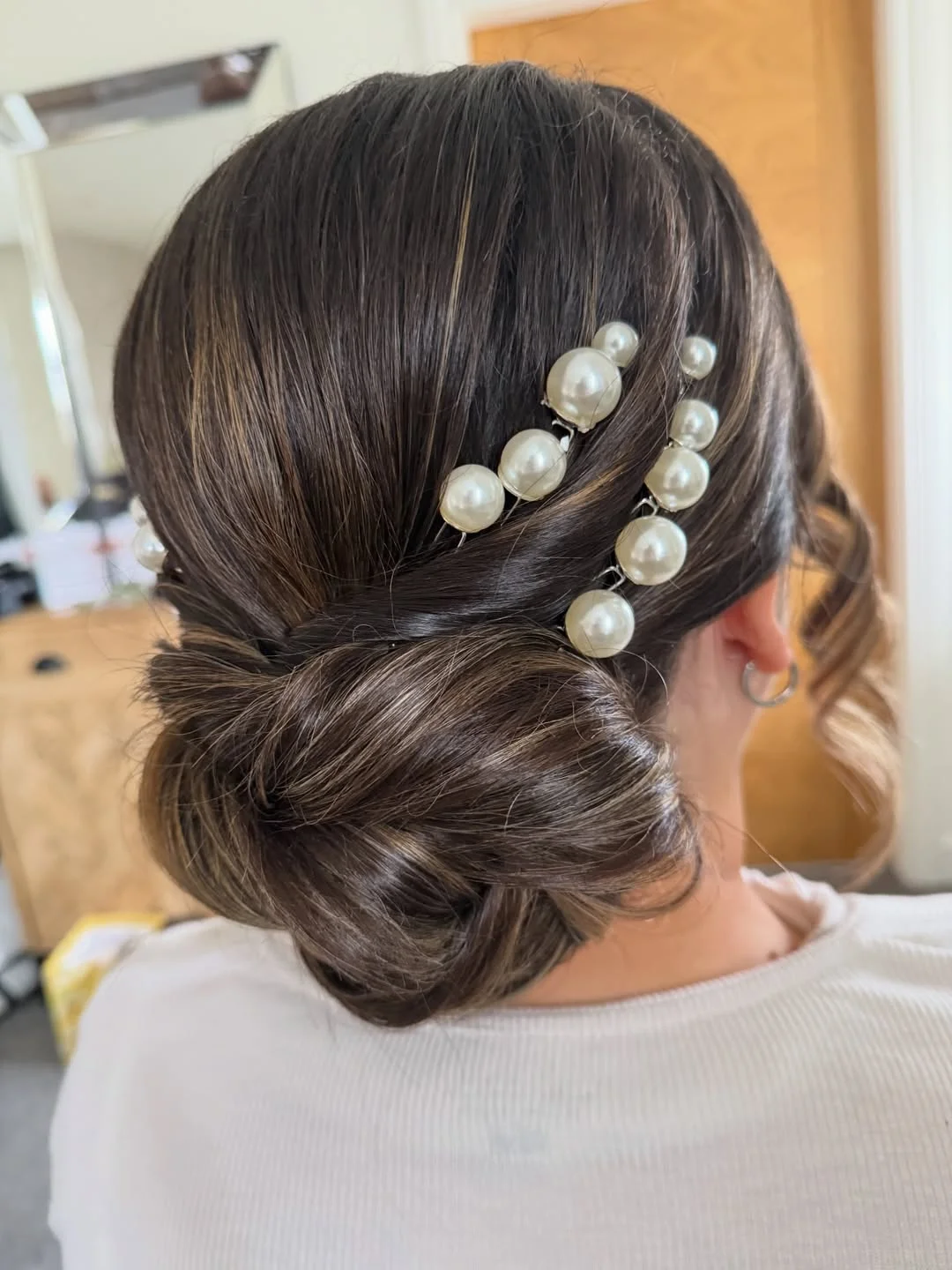 refined summer wedding guest hairstyles 2026 Sleek Pearl-Accented Low Chignon