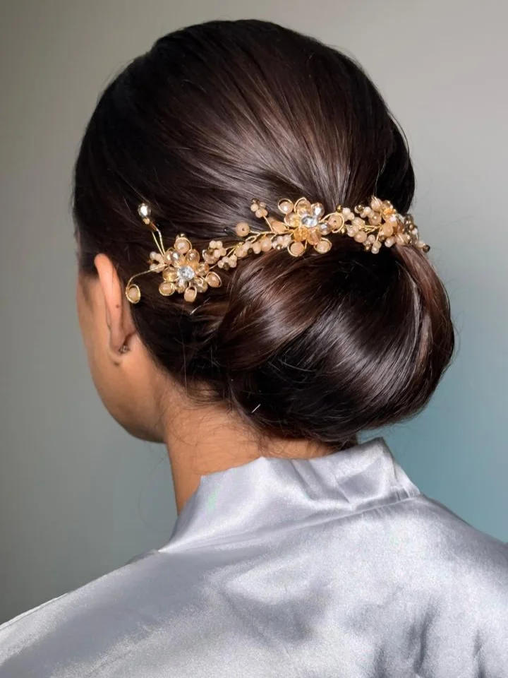 refined summer wedding guest hairstyles 2026 Glossy Espresso Low Bun With Gold Floral Barrette