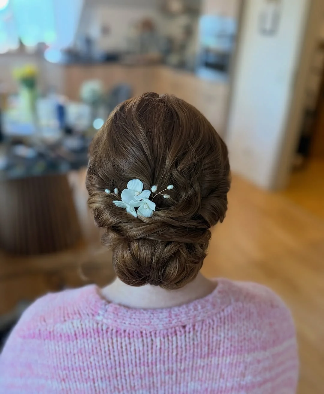 refined summer wedding guest hairstyles 2026 Classic Glossy Chignon With Minimal Floral Accent