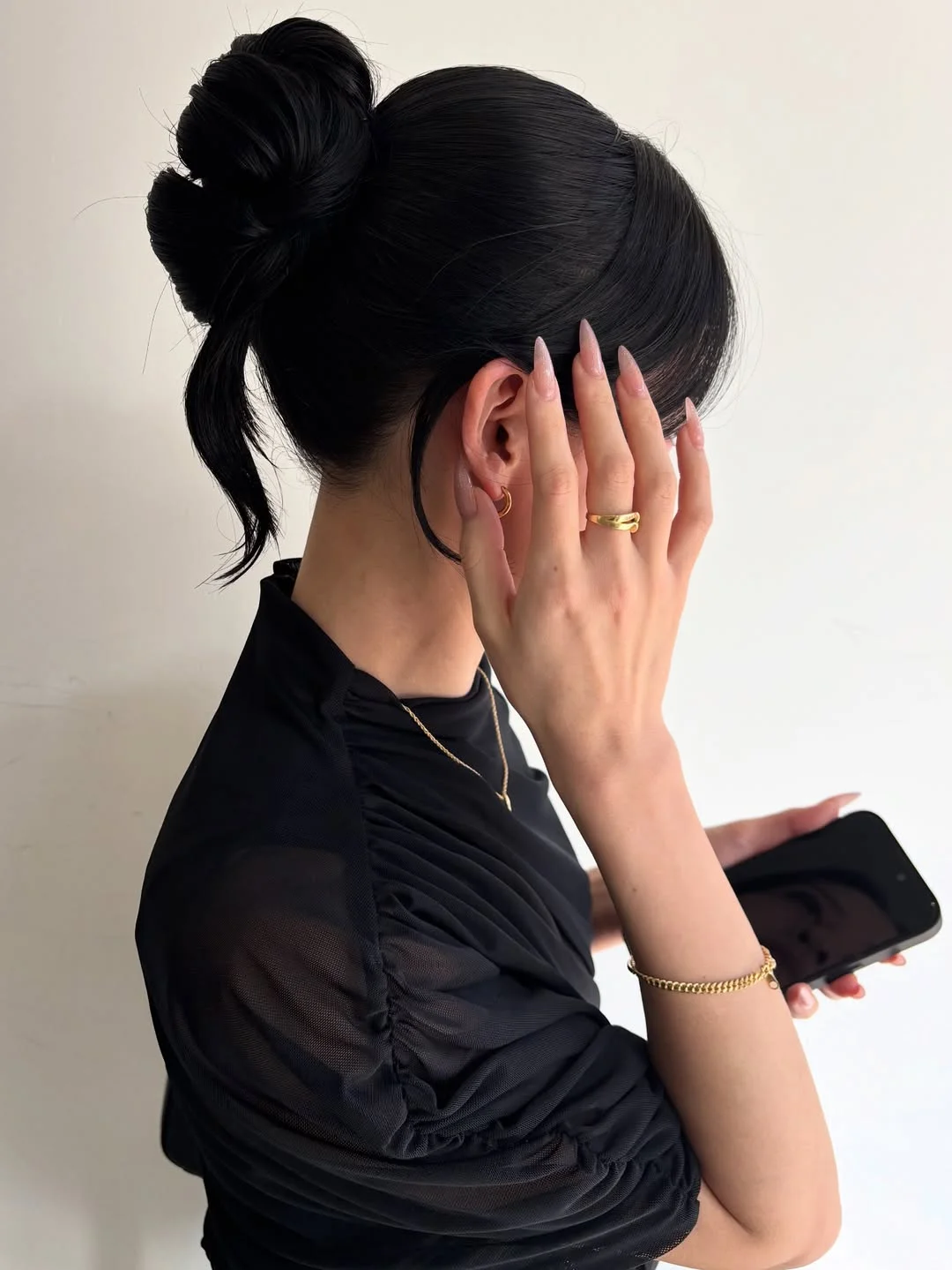 sleek summer updo hairstyles 2026 Glossy Jet Black Sculpted Bun With Face-Framing Pieces