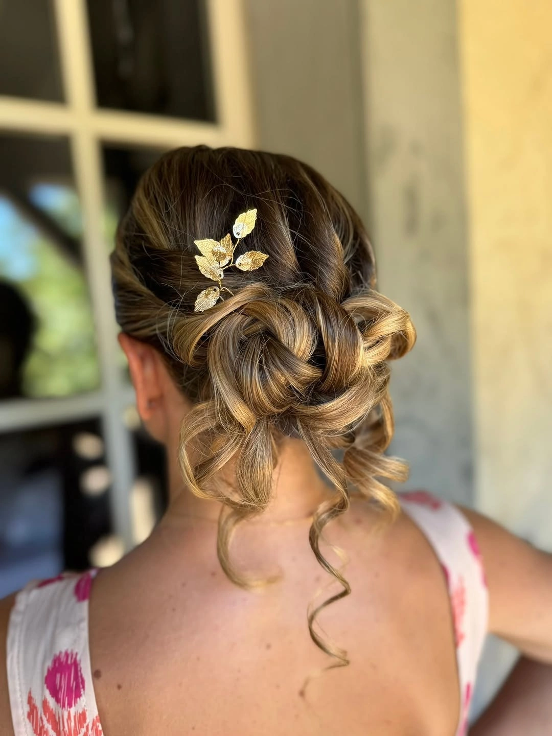 Fall hairstyles for wedding guests 2026 Romantic Twisted Low Chignon With Golden Leaf Accent