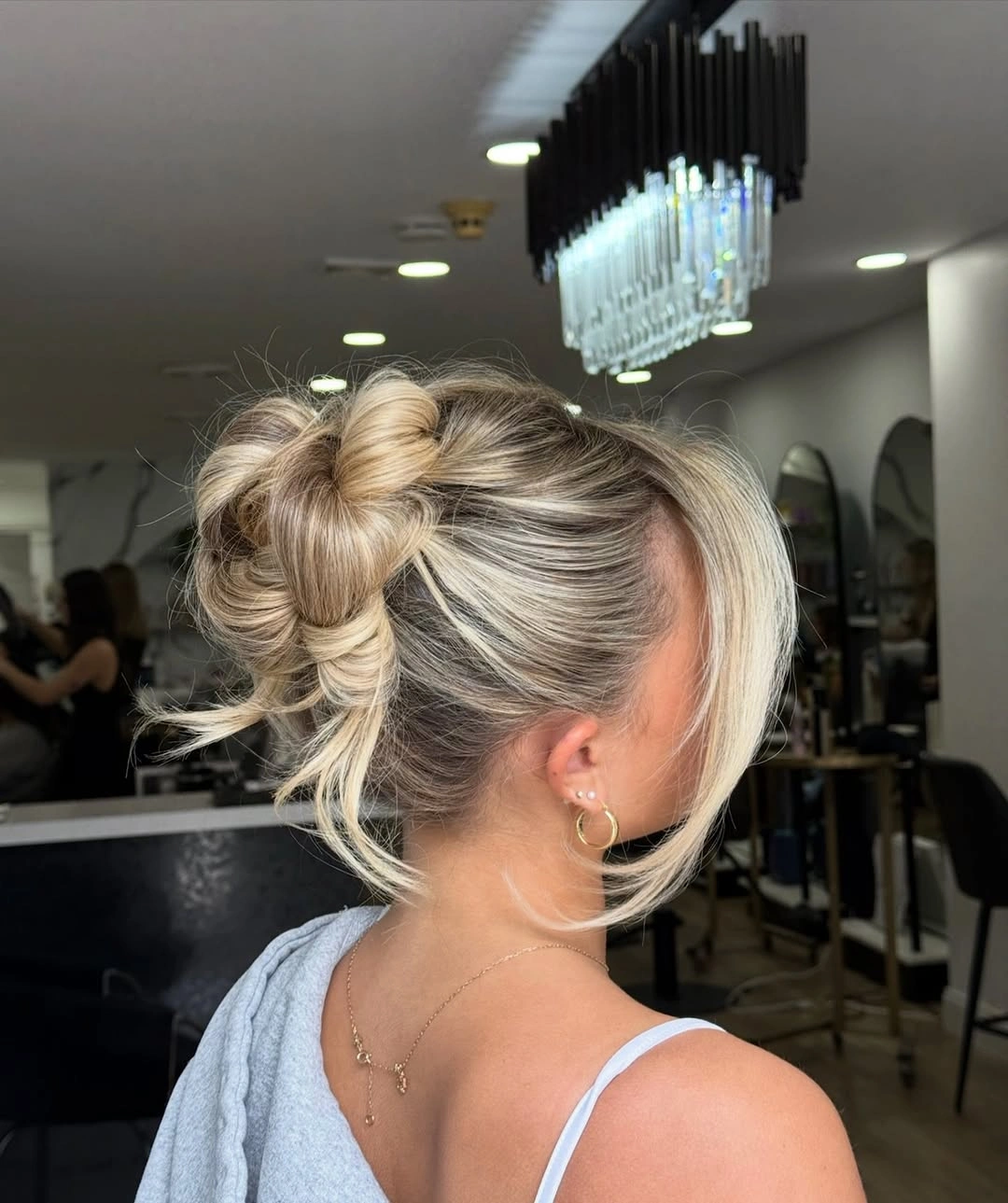 Fall hairstyles for wedding guests 2026 Modern Twisted Low Bun With Soft Blonde Curtain Pieces