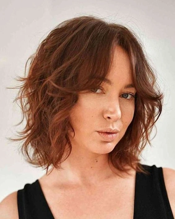 fall medium haircuts 2026 Soft Auburn Wavy Bob with Curtain Fringe
