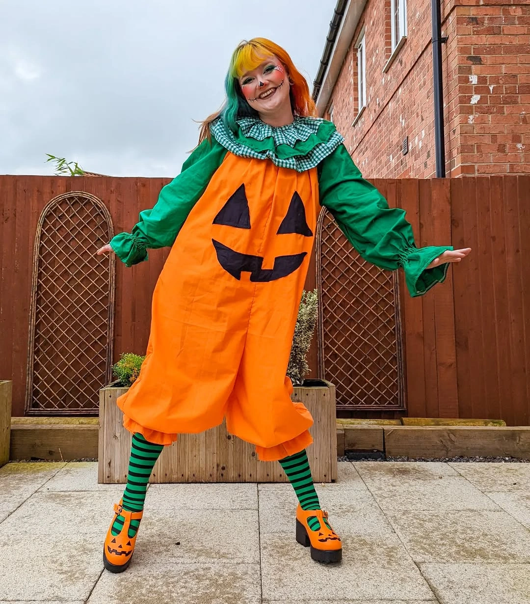 Orange pumpkin tunic costume with green sleeves striped leggings and orange shoes
