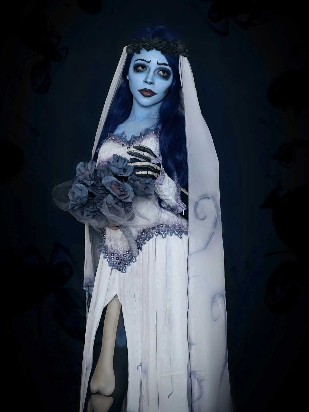 White corpse-bride-style gown with dark corset detail veil and dark bouquet