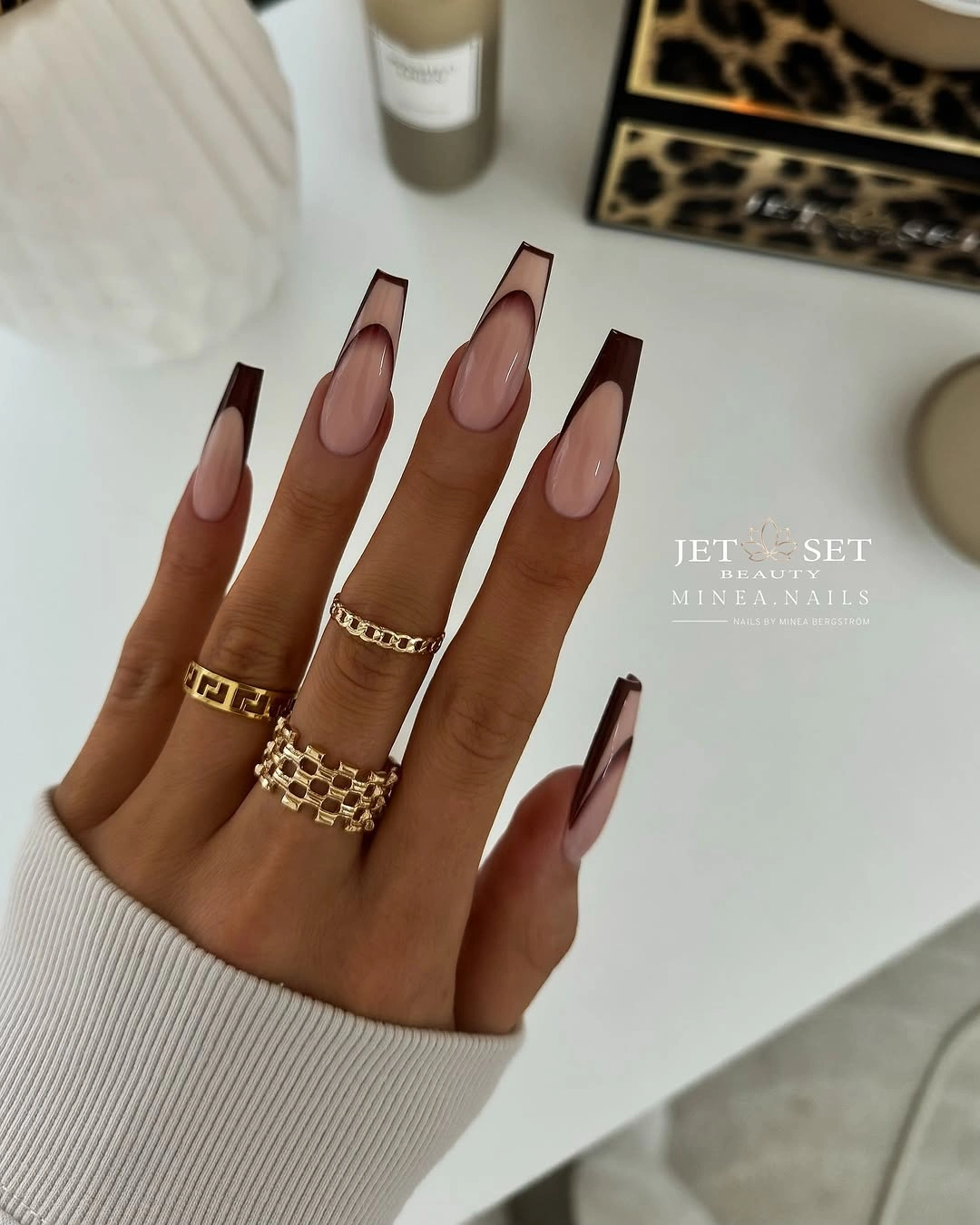 Long pale nails with deep brown outline details around the edges