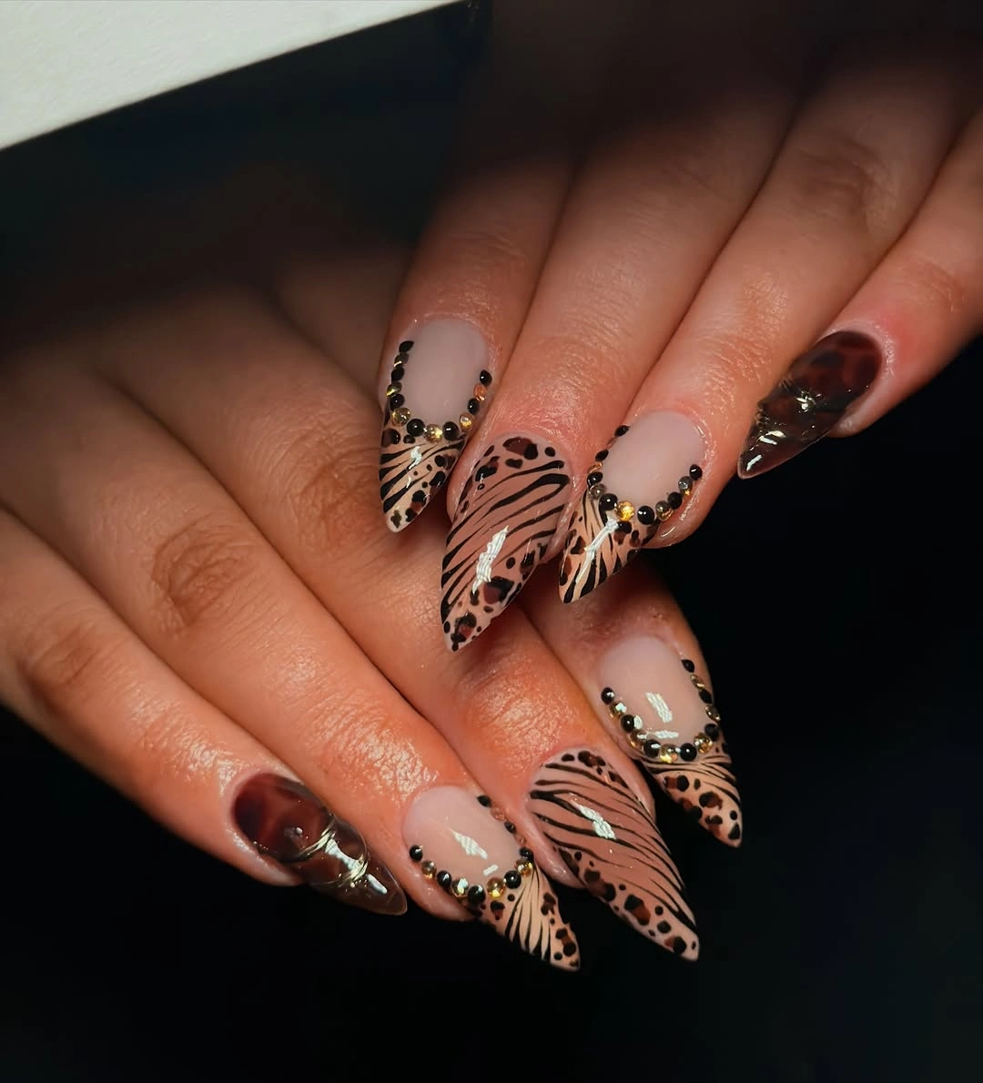 Long almond brown nails with pale patterned tips and dark curved stripes