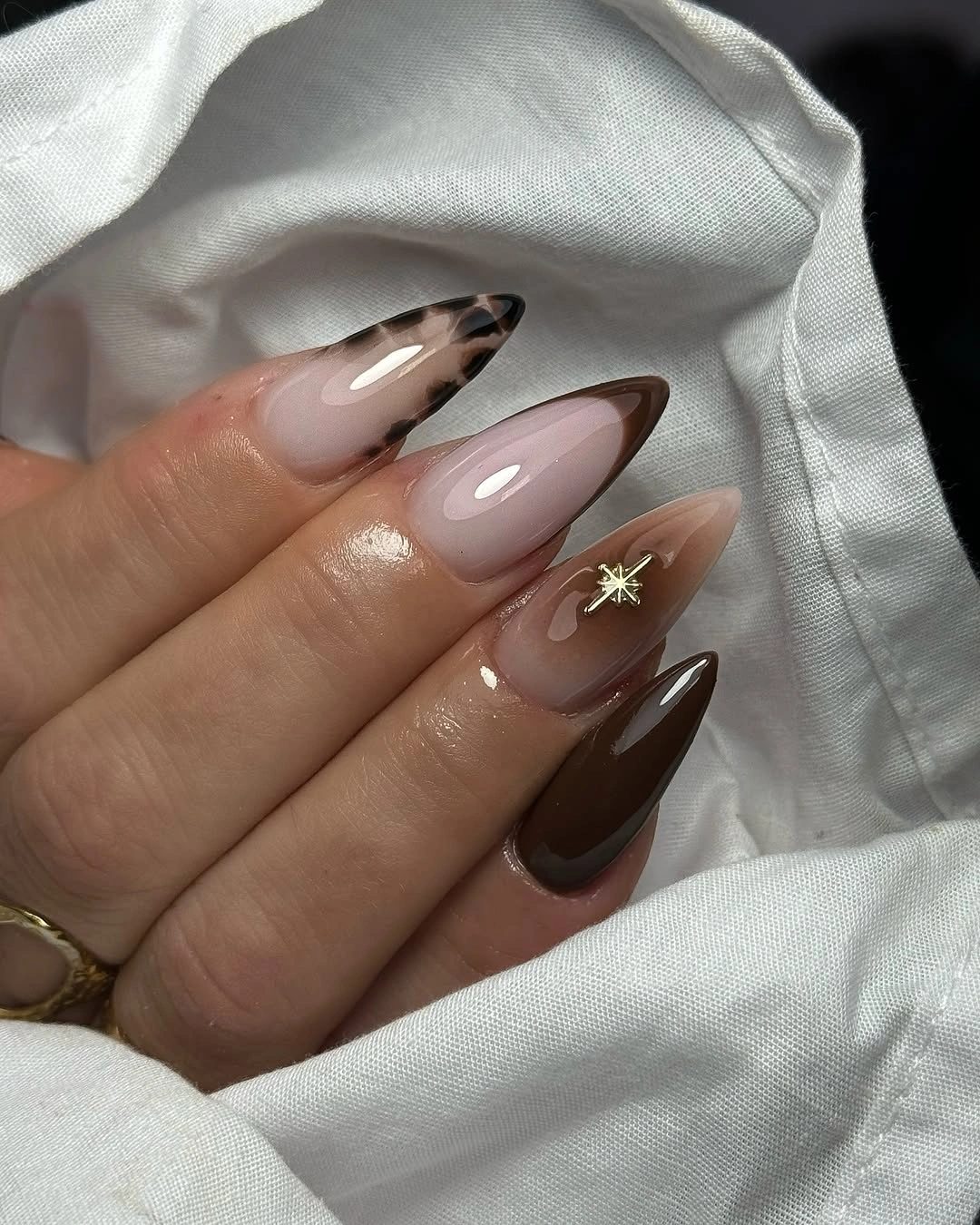 Almond milky nails with brown side panels and one gold star accent
