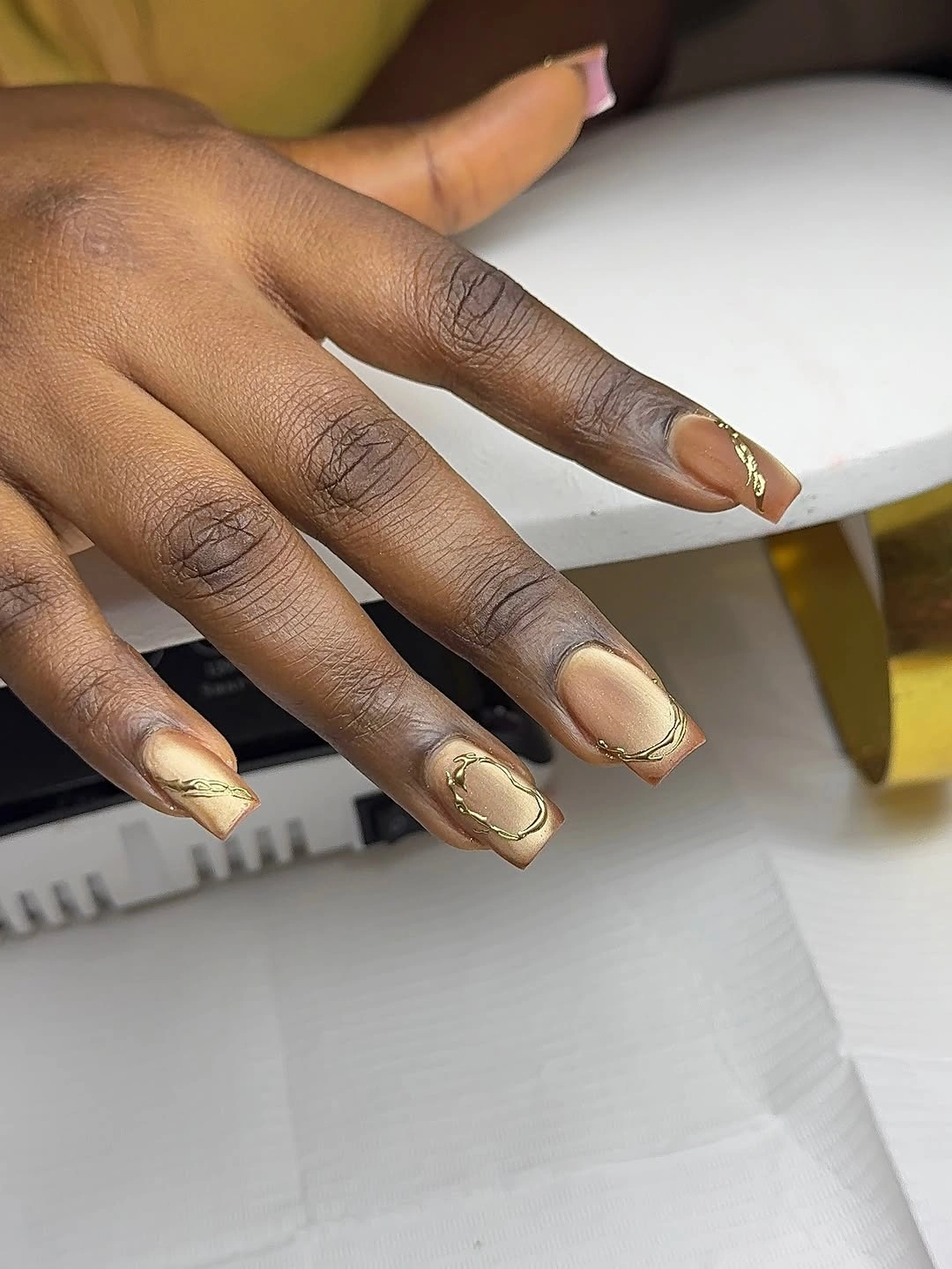 Medium almond nude nails with delicate brown and gold line accents