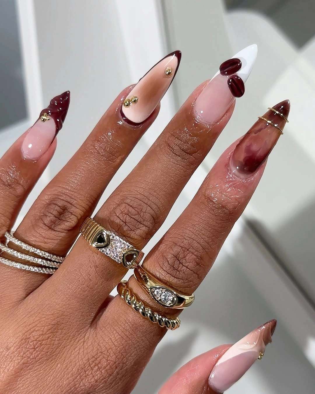 pink almond nails with burgundy accents and slim gold details