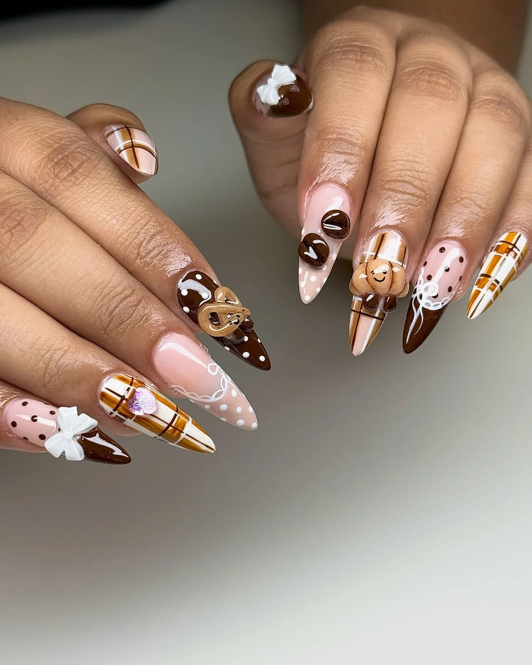nude pointed nails with brown graphics and white linework