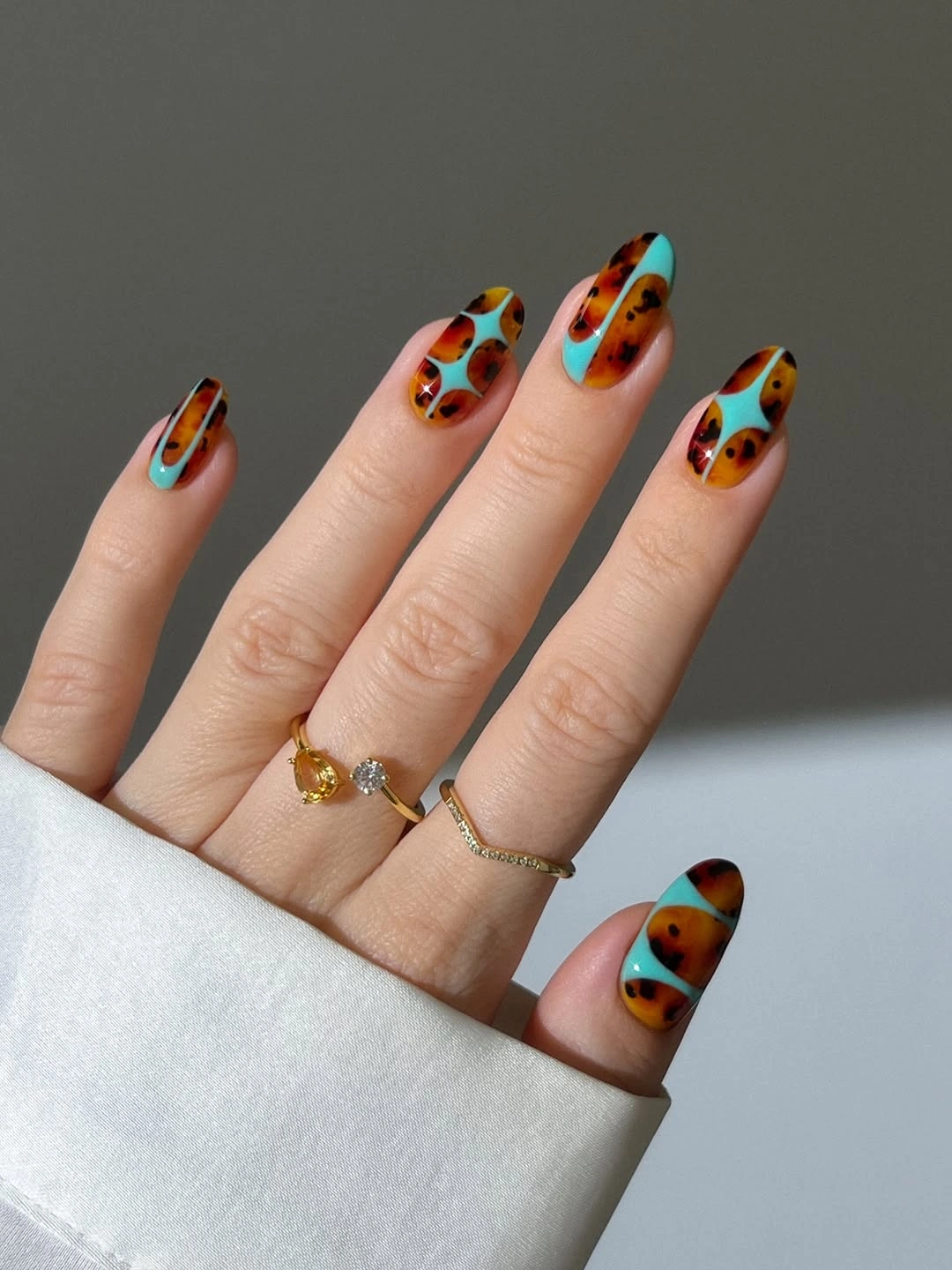 short turquoise nails with orange brown and black spots