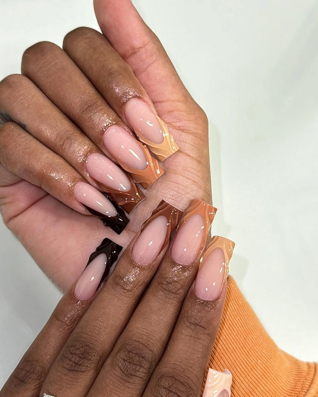 soft pink almond nails with orange tips and black accents