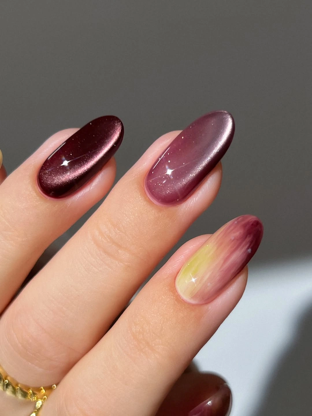deep plum almond nails with one warm gradient accent