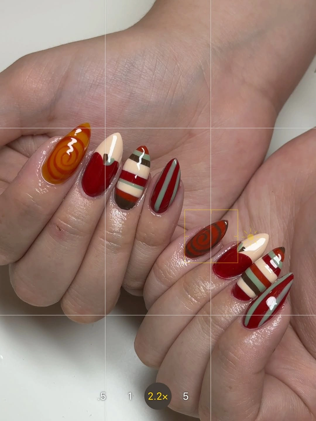 nude nails with orange, red, cream, and green striped accents