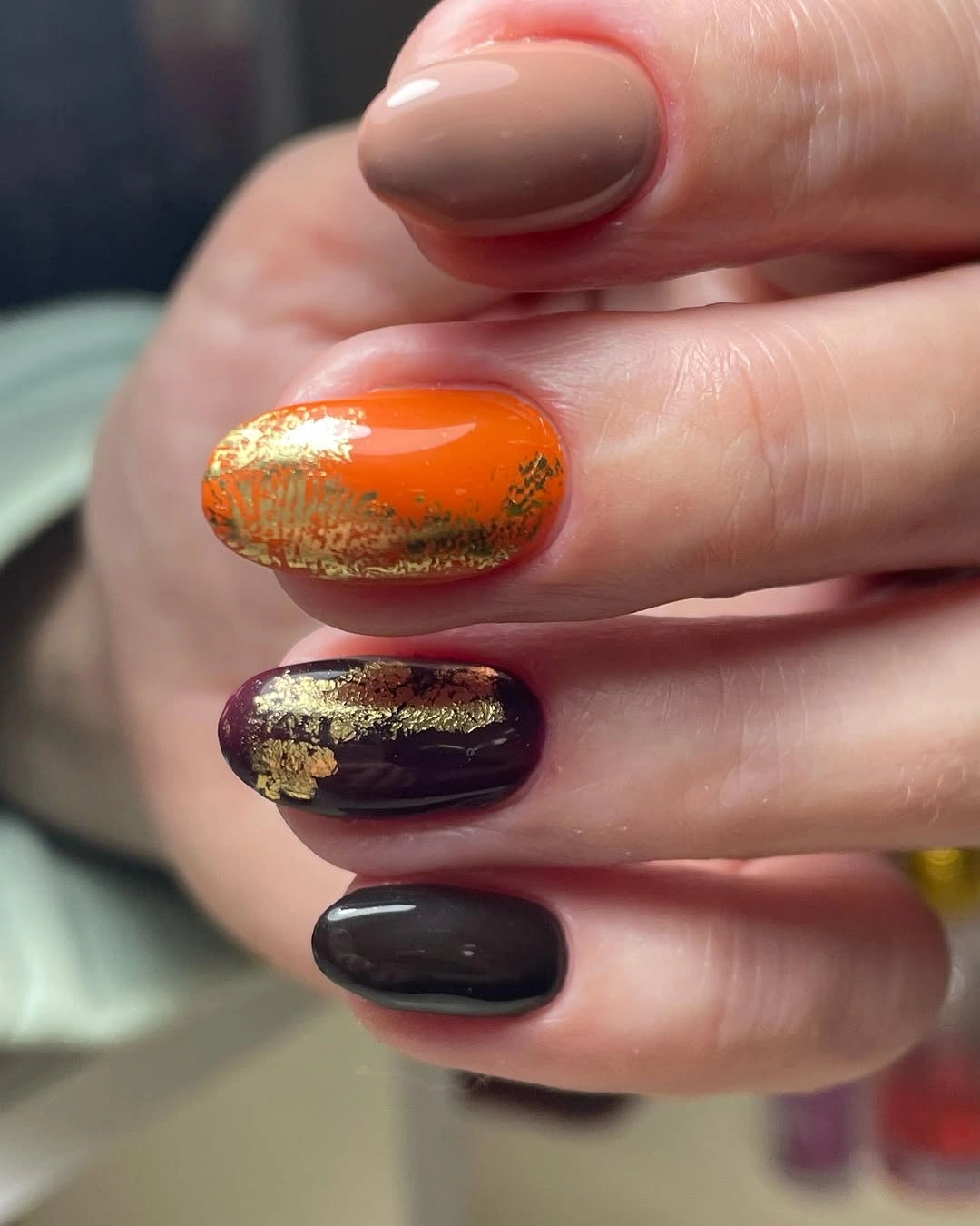 Short rounded multicolor nails with gold-toned accents