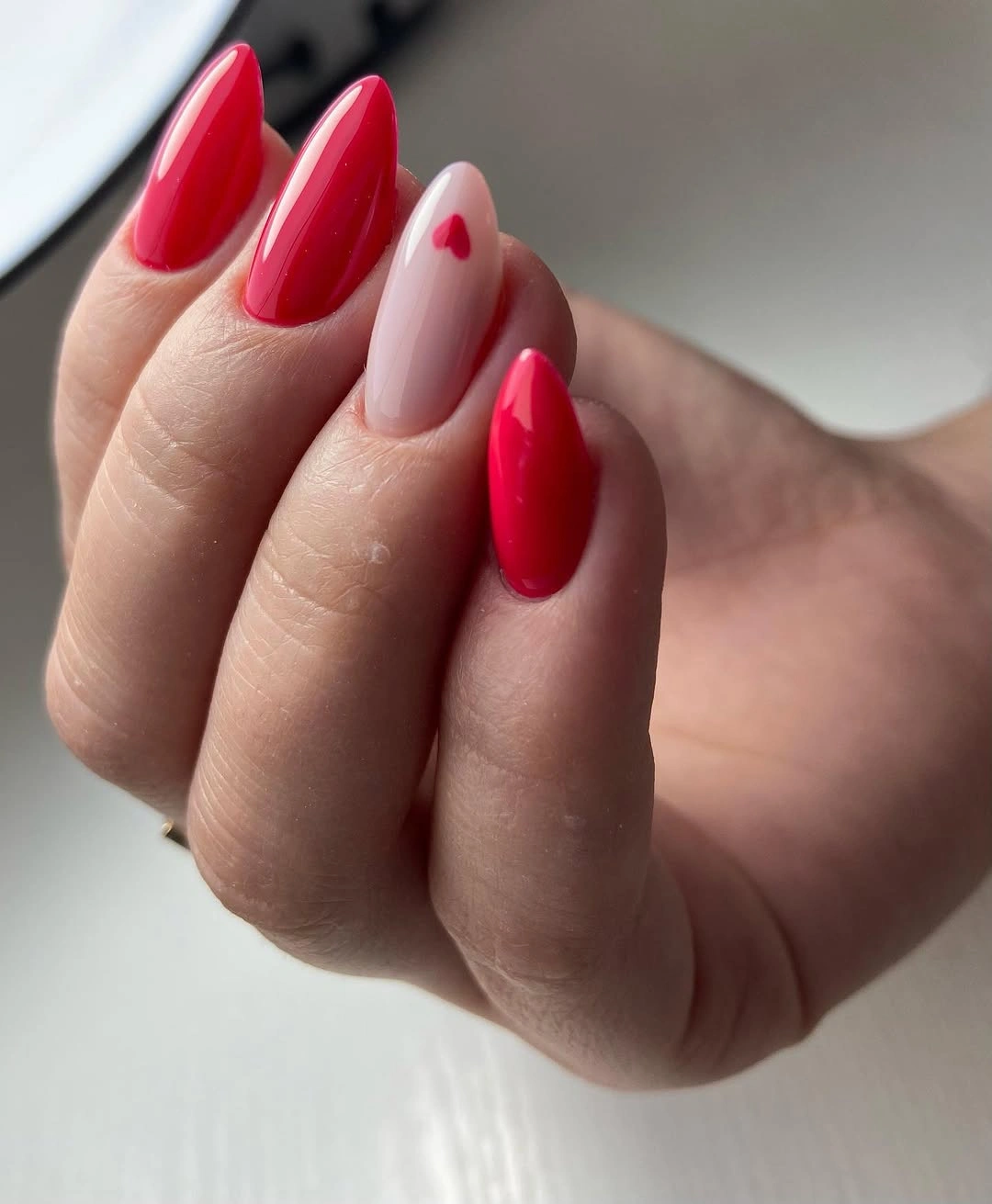 Red pink almond nails with one pale accent