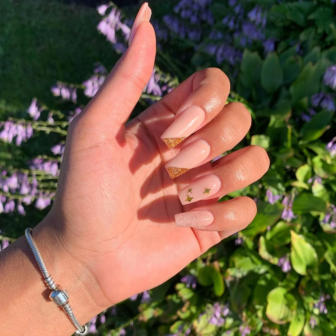 Nude pink tapered nails with gold glitter tips
