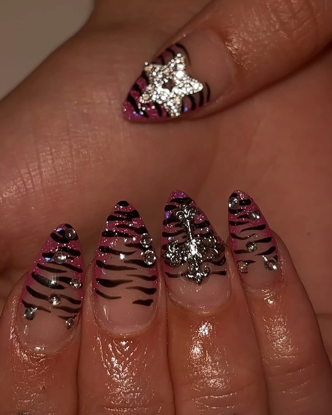 Pointed nude nails with pink glitter and silver charms