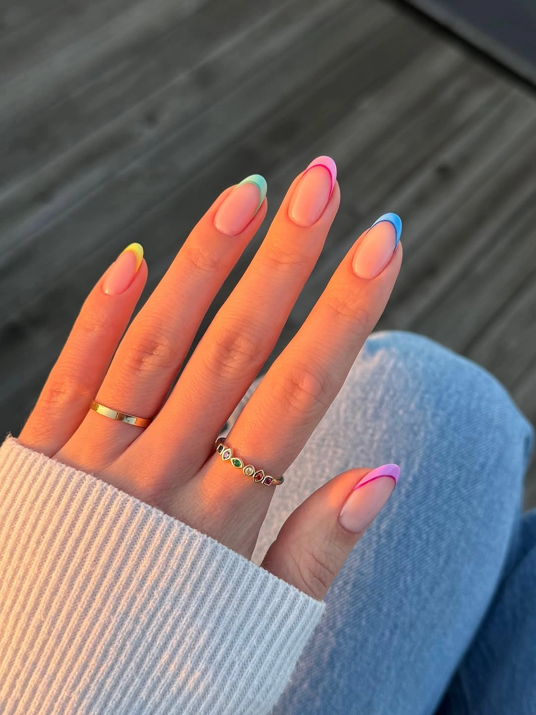Sheer almond nails with rainbow French tip colors