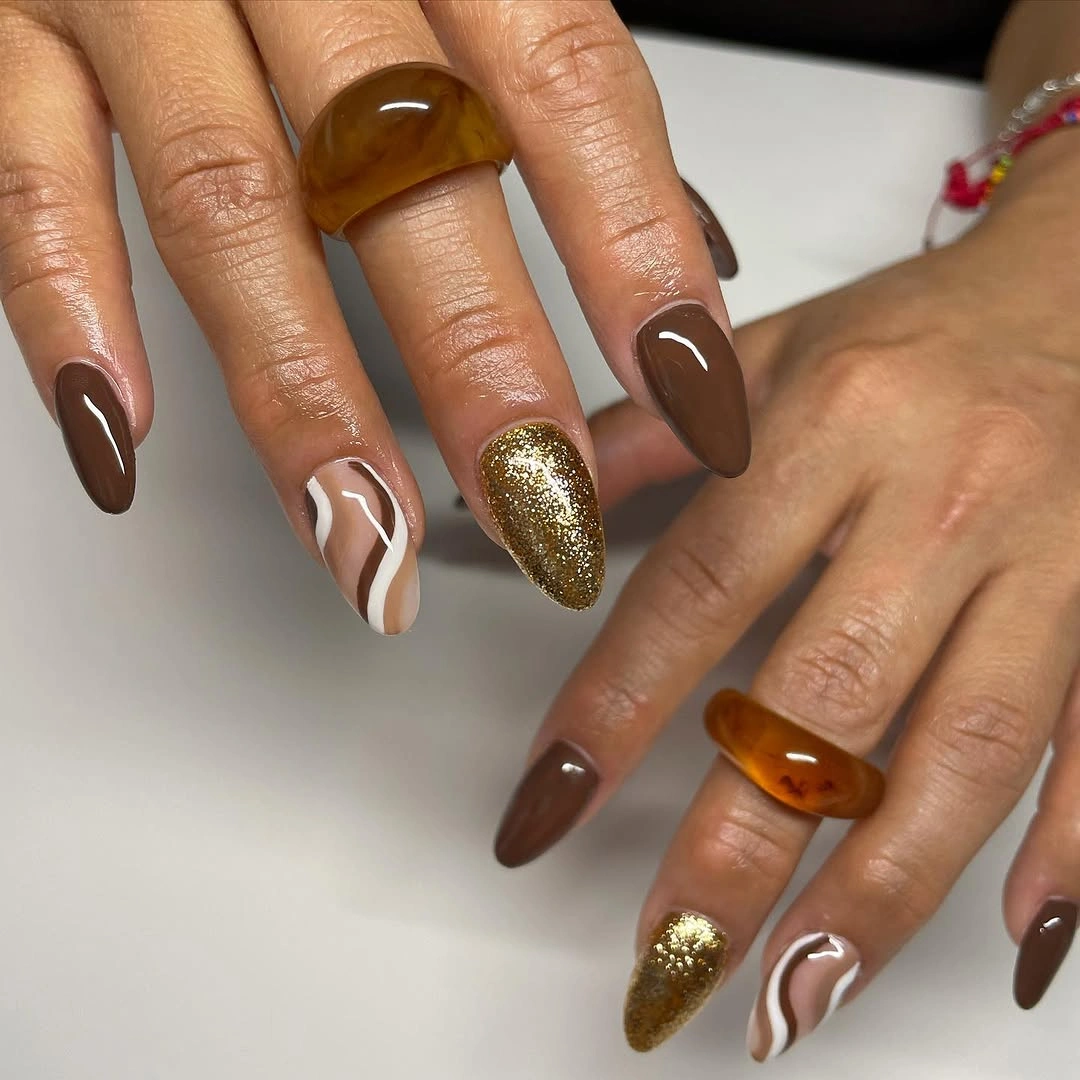 Chocolate brown almond nails with gold glitter accents
