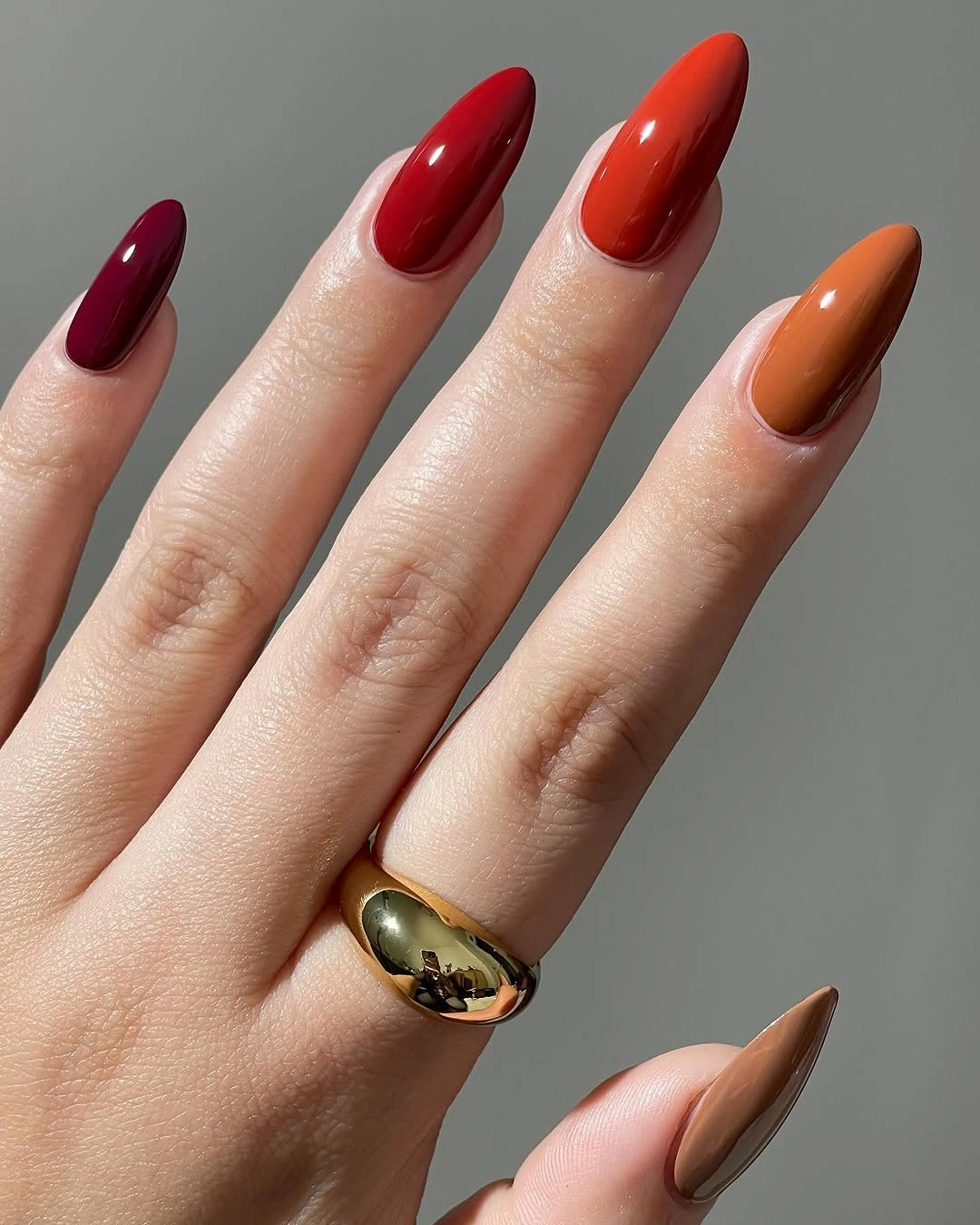 Glossy almond nails in burgundy rust and brown tones