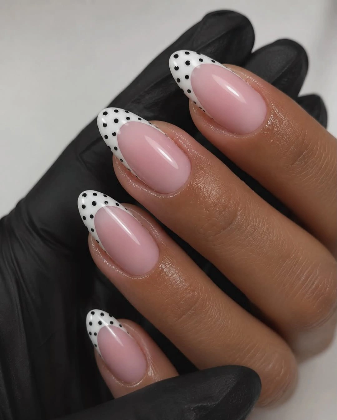 Pink almond nails with black polka dot French tips