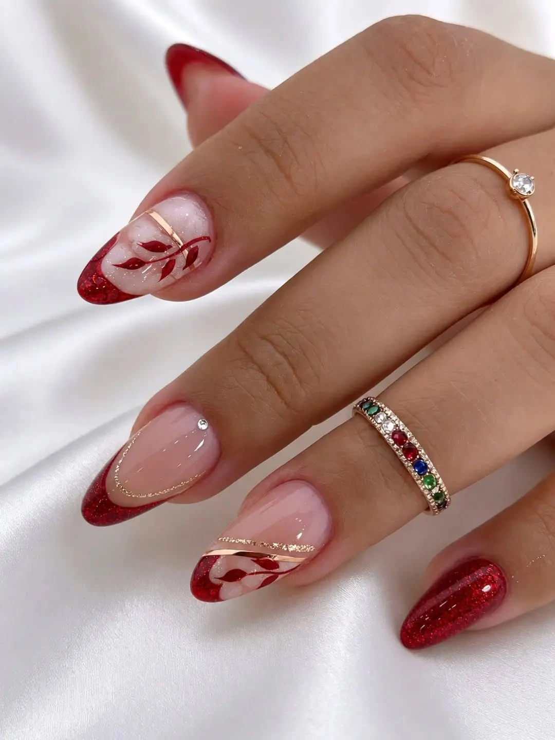 Almond nails with red glitter tips and leaf details