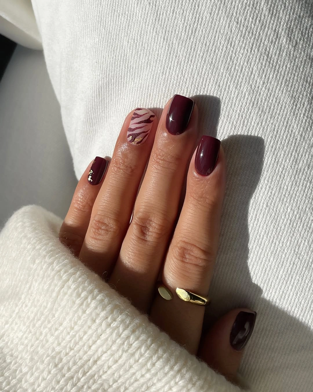 Medium burgundy nails with one small animal-like accent