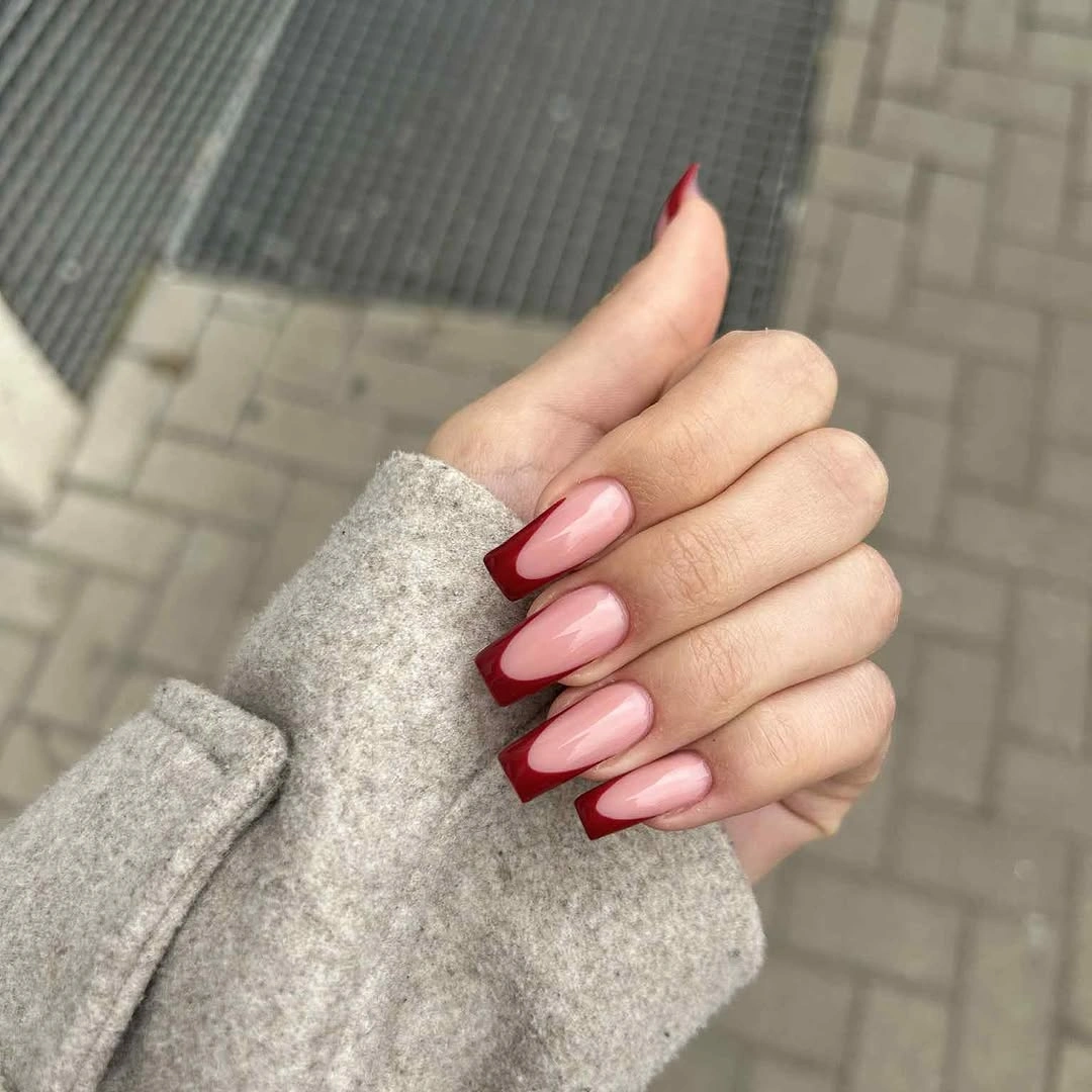 Medium almond nails with nude bases and burgundy French tips