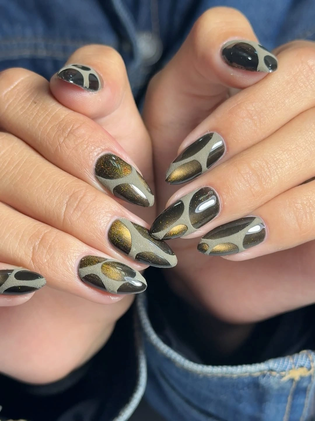 Pale gray almond nails with black shapes and muted gold accents