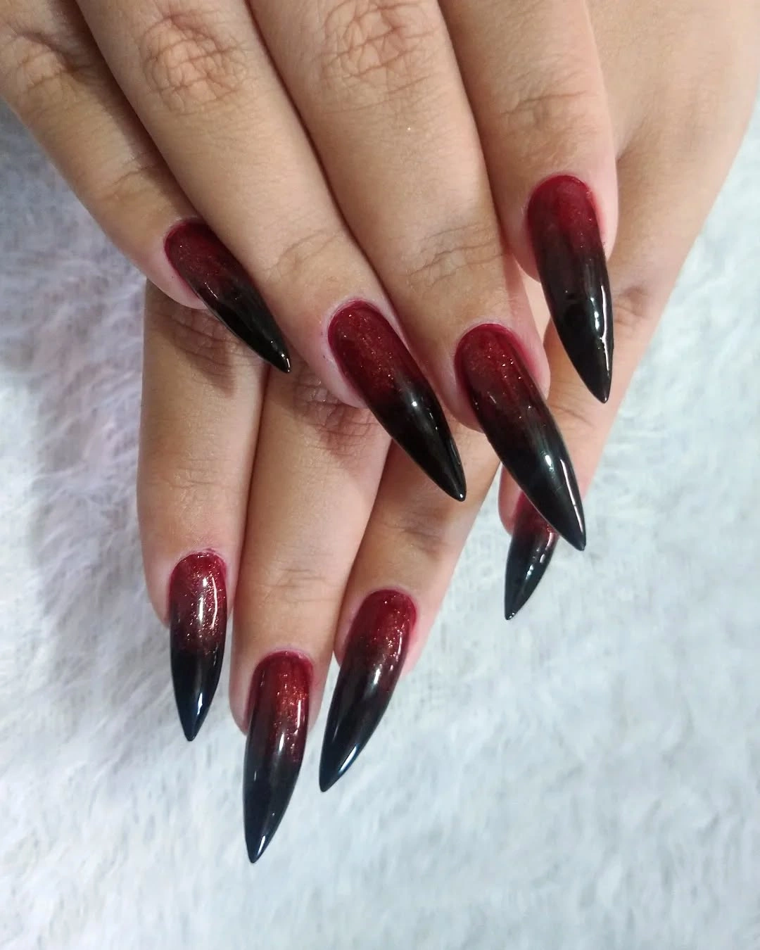 Long pointed red shimmer nails fading into black tips