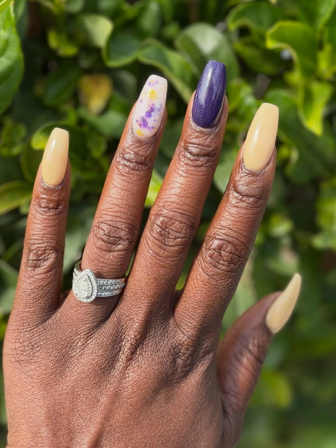 Long yellow and purple almond nails with small floral accent