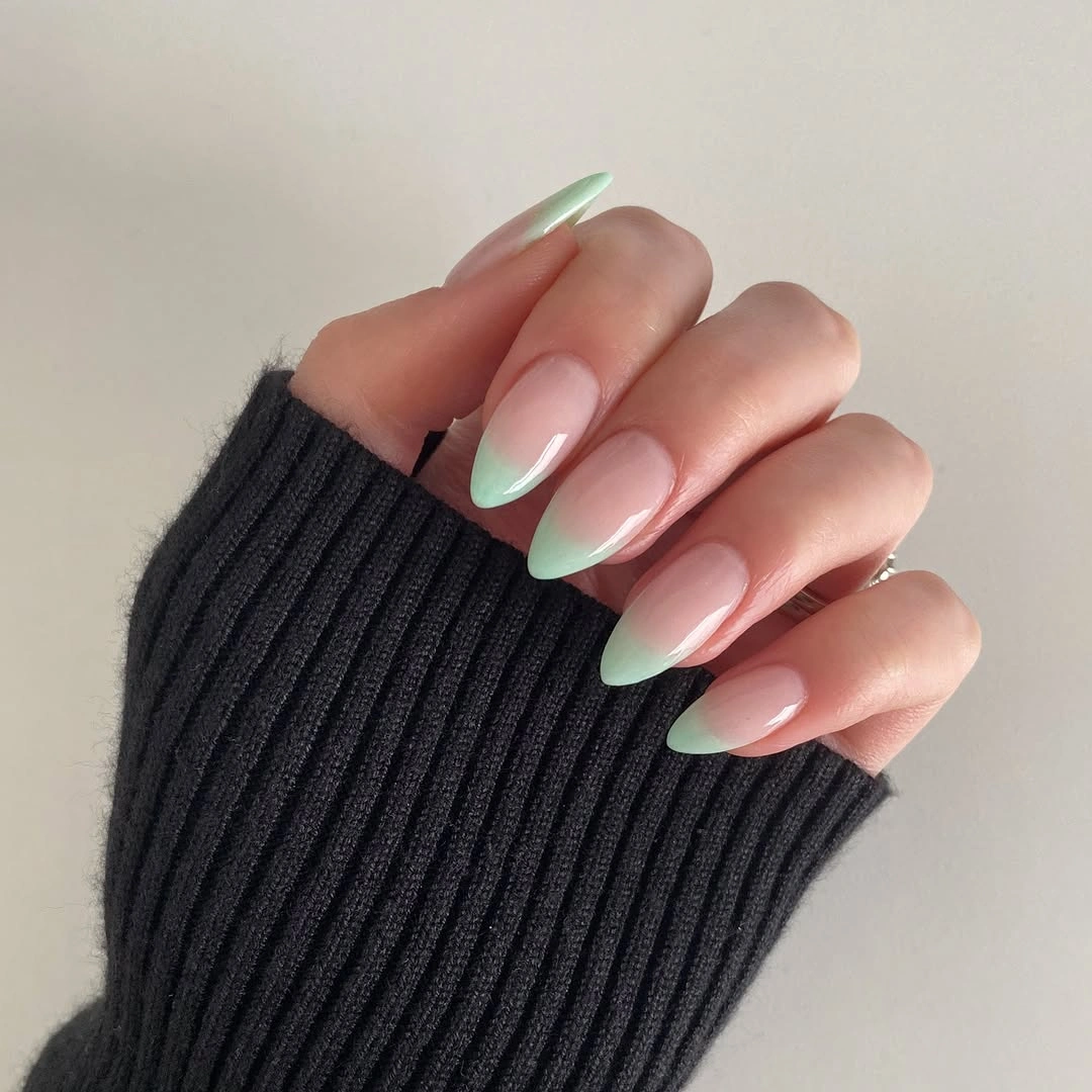 Nude almond nails with slim muted green French tips