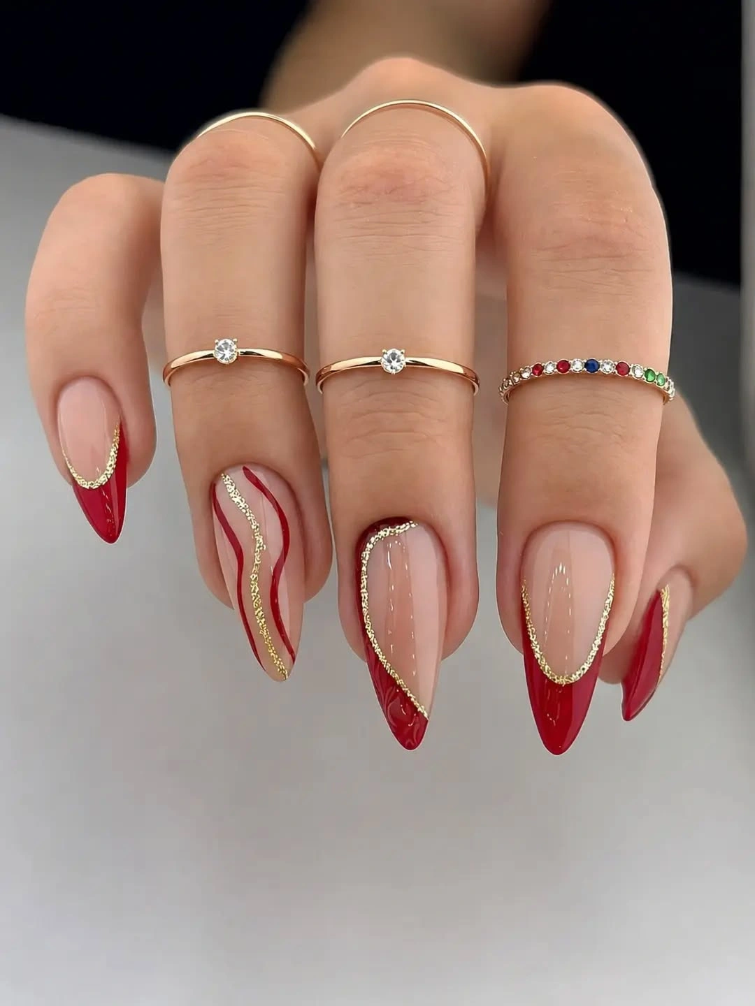Long almond nails with curved red French tips and fine metallic lines