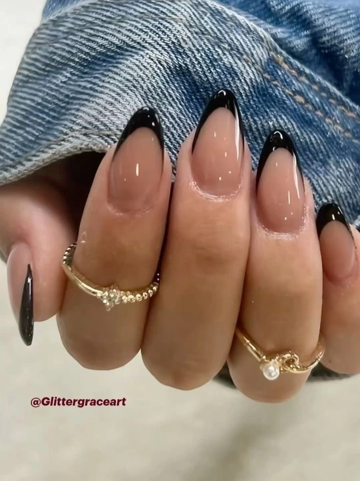 Long almond nails with black French tips and warm metallic contours
