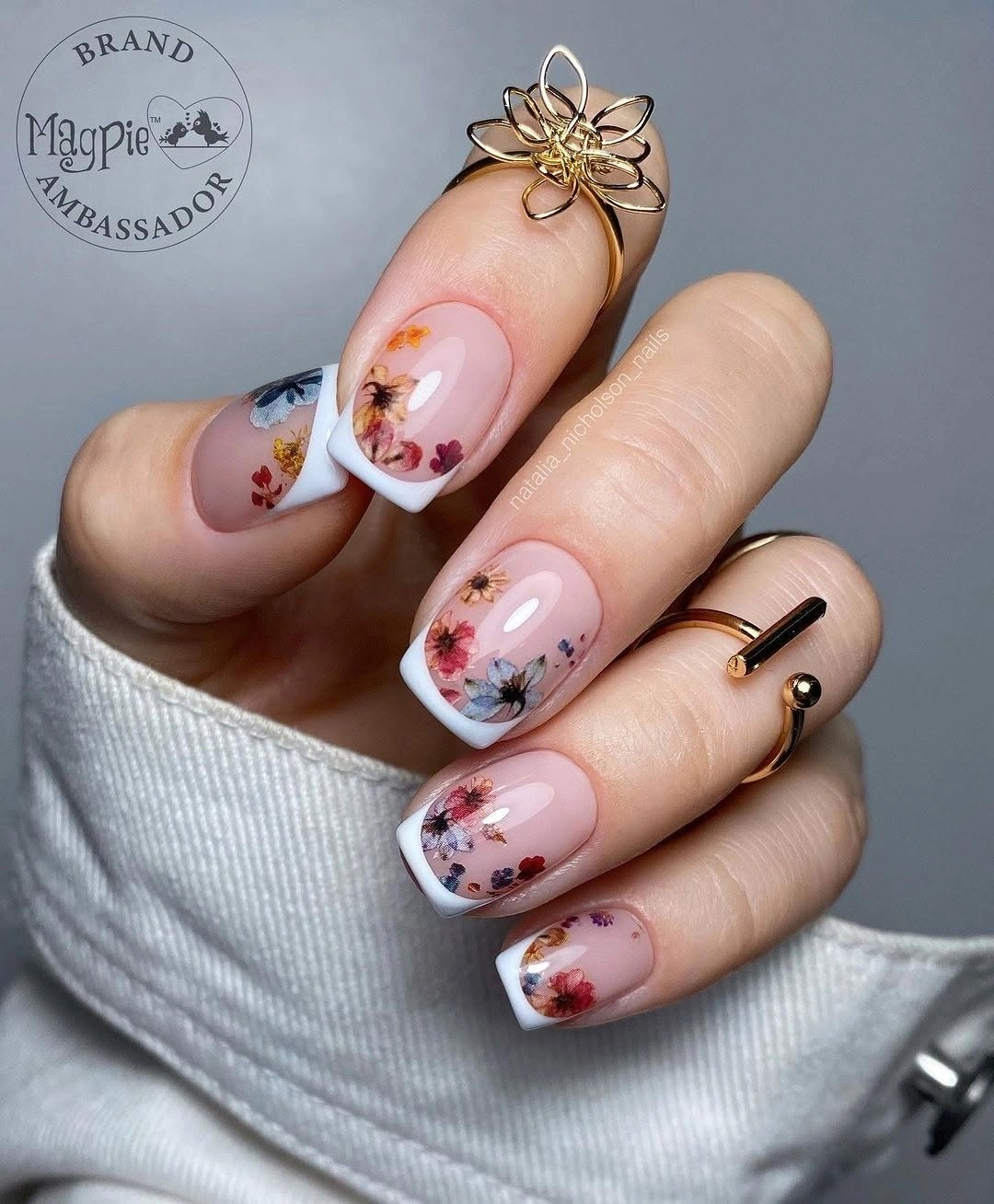 Short square pink nails with white tips and tiny floral accents