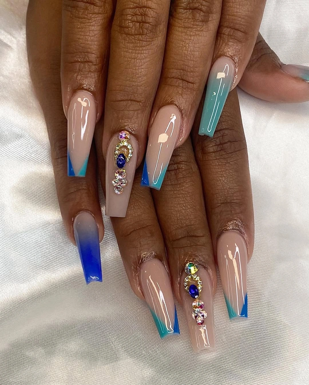 Long nude nails with blue turquoise tips and jeweled accents