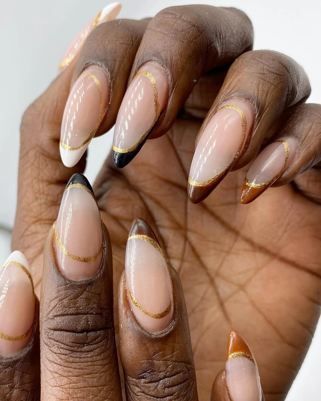 Long pointed nude nails with white brown and gold double-lined tips