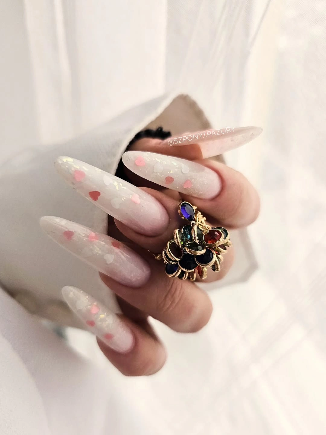 Soft pink almond nails with pale shimmer and delicate accents