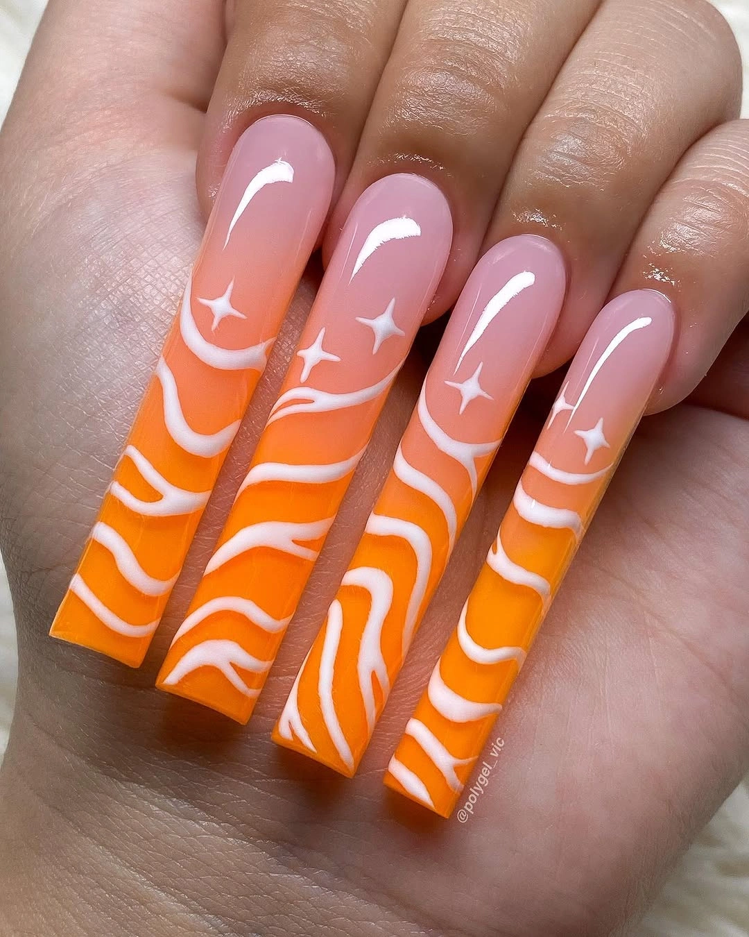 Bright orange coffin nails with white waves and star motifs