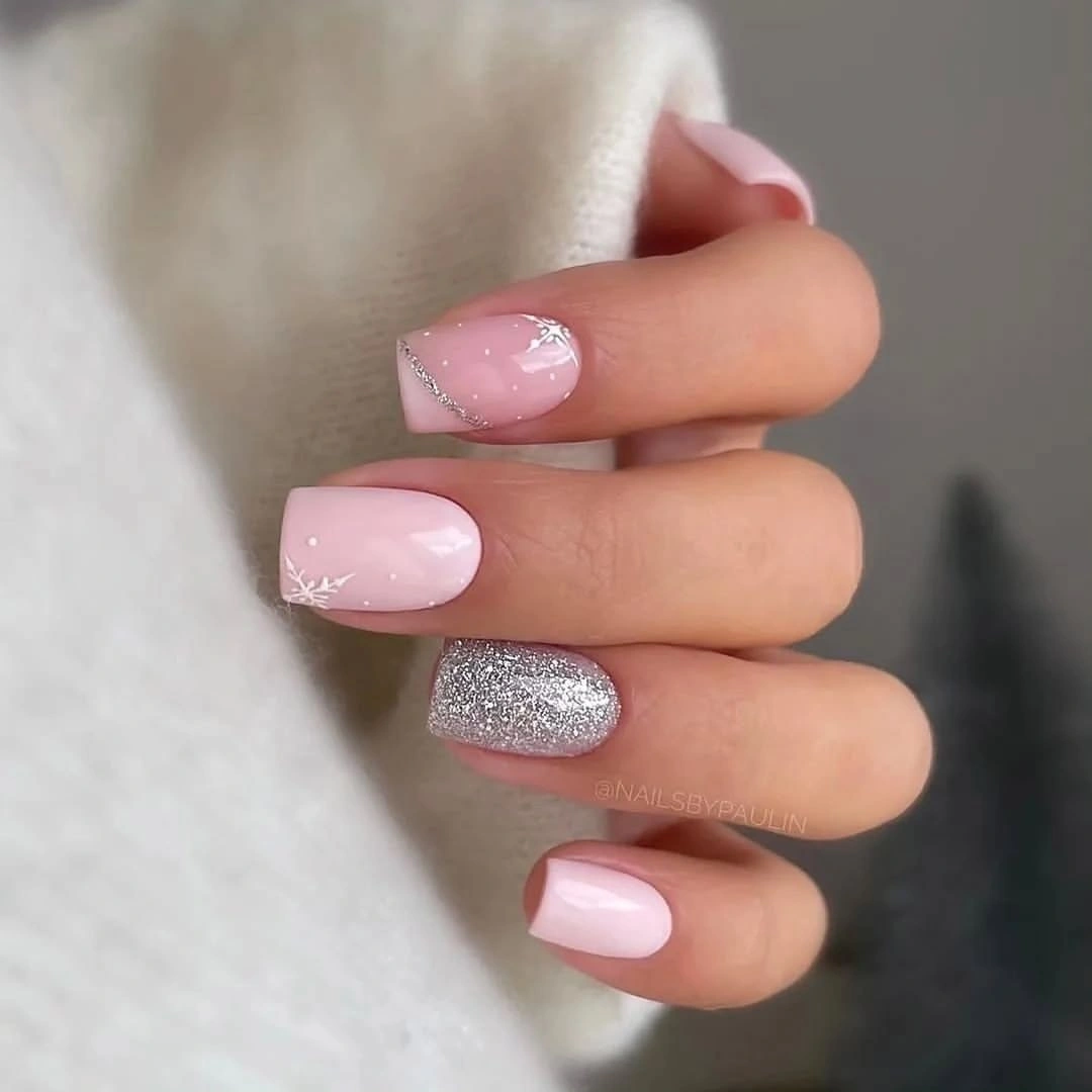 short square manicure featuring pale pink glossy nails, one silver glitter accent, and delicate white details