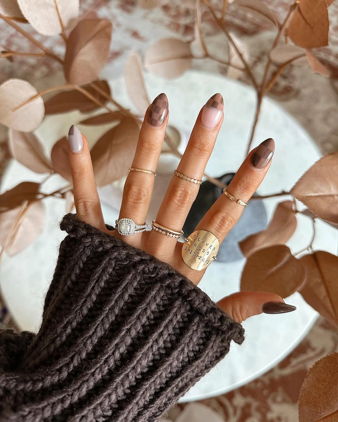 long almond manicure featuring chocolate brown nails, nude accents, and muted plaid tip details