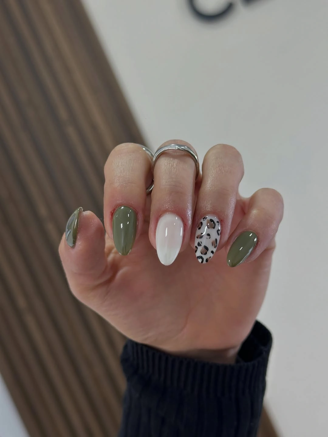 medium almond manicure featuring olive nails, a milky white accent, and a leopard print accent