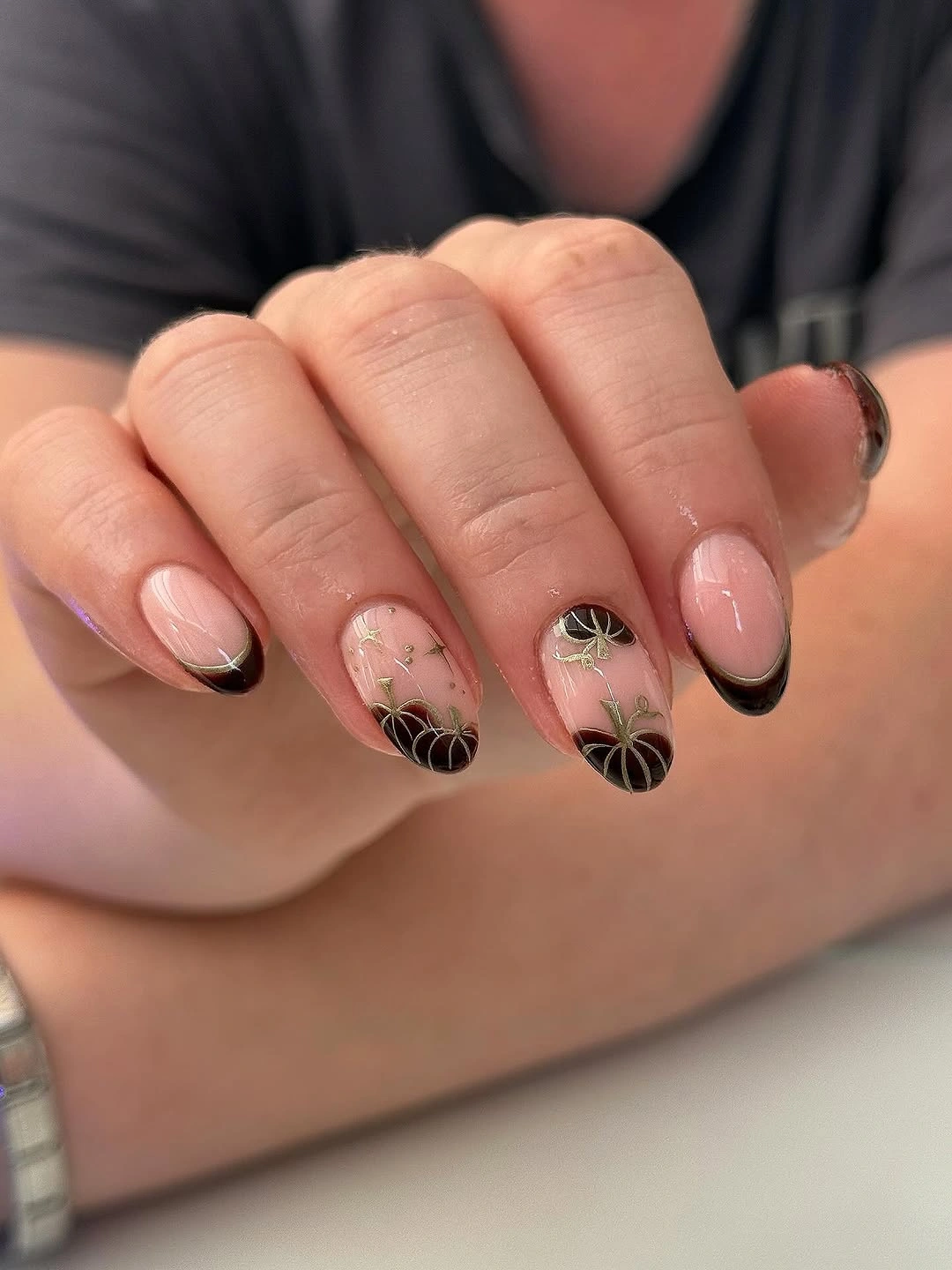 short oval manicure featuring black French tips, pumpkin line art, gold stems, and small star details