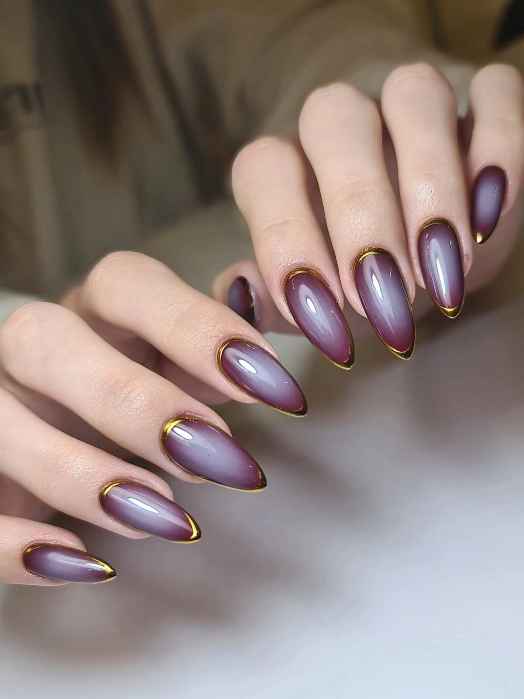 long plum purple nails with fine gold-looking outlines