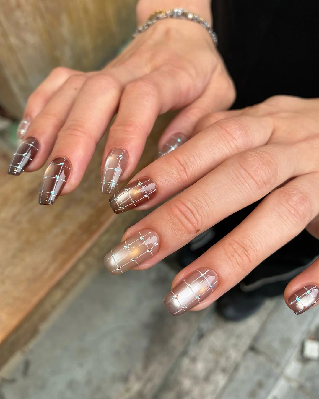 Translucent square nails with brown white grid bands and metallic accents